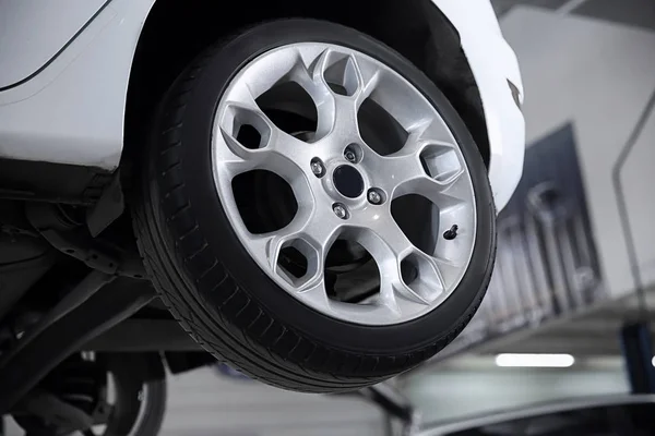 Car on lift at tire service, closeup