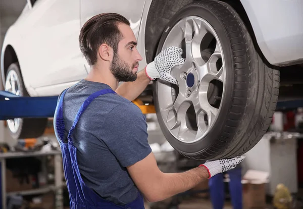 Mladí mechanik mění kolo na pneuservis — Stock fotografie