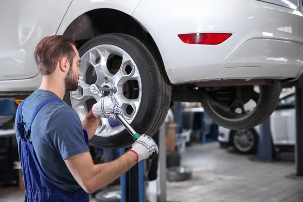 Mladí mechanik mění kolo na pneuservis — Stock fotografie