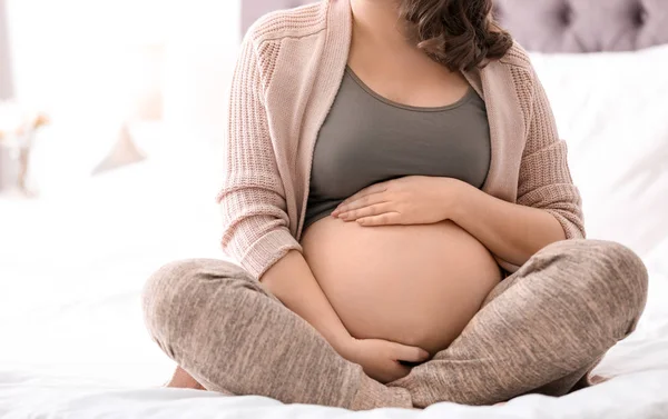 임신 한 젊은 여자 가집 침대에 앉아 있다 — 스톡 사진