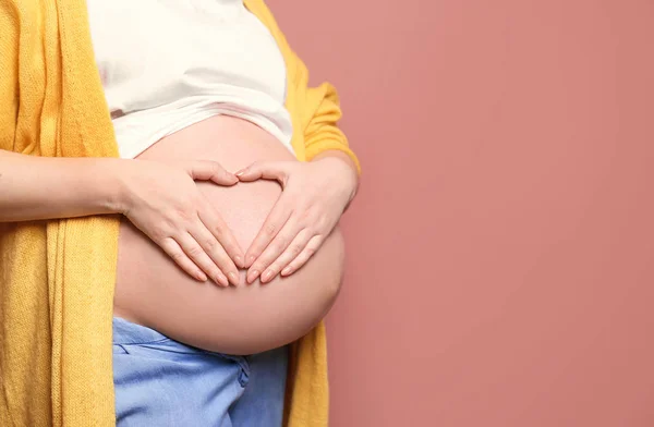Молодая беременная женщина в повседневной одежде на цветном фоне — стоковое фото