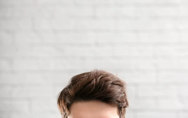 Young man with beautiful hair on brick wall background, closeup — Stock Photo, Image