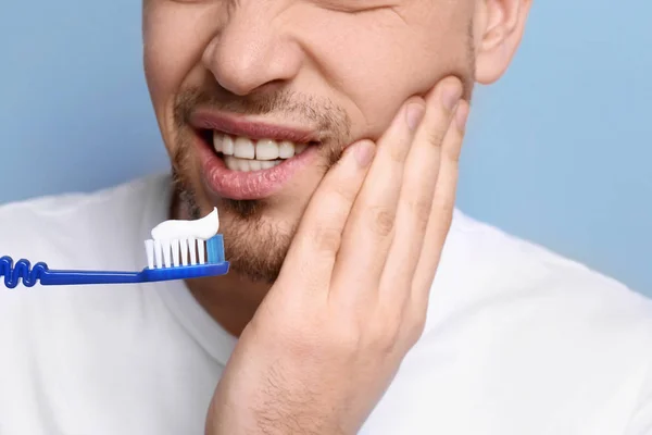 Ung Man lider av tandvärk på grå bakgrund — Stockfoto