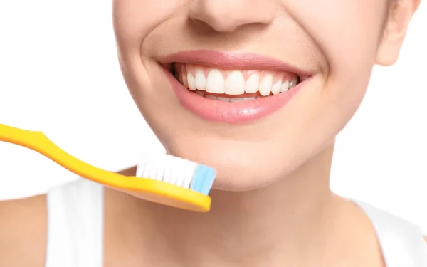 Jovem mulher escovando os dentes no fundo branco, close-up — Fotografia de Stock