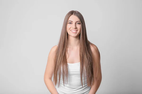 Porträtt av ung kvinna med långa vackra hår på ljus bakgrund — Stockfoto
