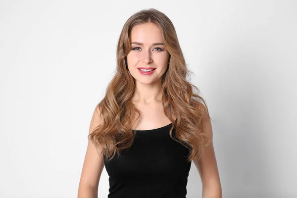 Portret van een jonge vrouw met lange mooie haren op lichte achtergrond — Stockfoto