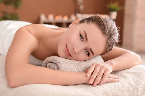 Ung kvinna ligger på massage bord i spa salong — Stockfoto