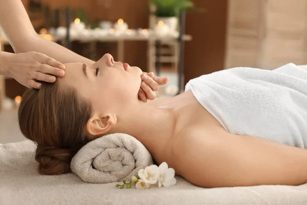 Giovane donna godendo massaggio facciale nel salone spa — Foto Stock