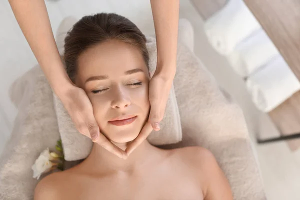 Mujer joven disfrutando de masaje facial en el salón de spa —  Fotos de Stock