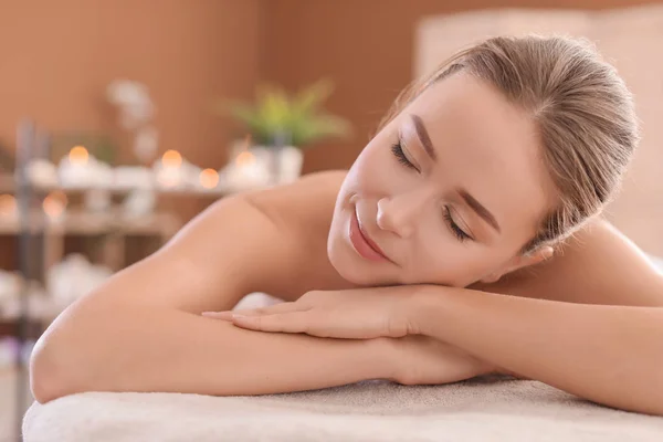 Young woman lying on massage table in spa salon — Stock Photo, Image