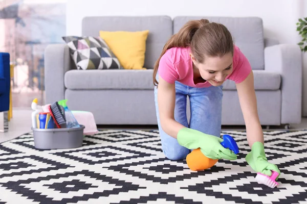Wanita membersihkan karpet di ruang tamu — Stok Foto