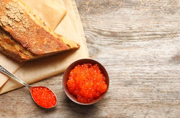 Tigela e colher com delicioso caviar vermelho na mesa — Fotografia de Stock