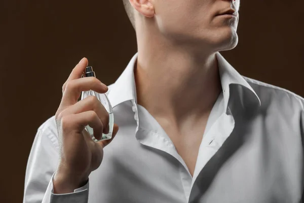 Hombre guapo en camisa usando perfume sobre fondo oscuro, primer plano — Foto de Stock