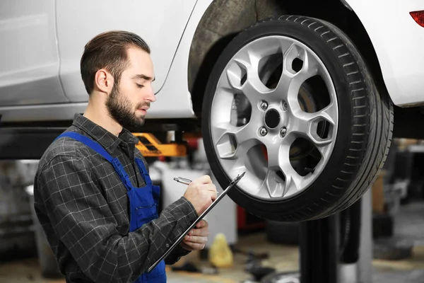 Young mechanic with clipboard at tire service Royalty Free Stock Photos