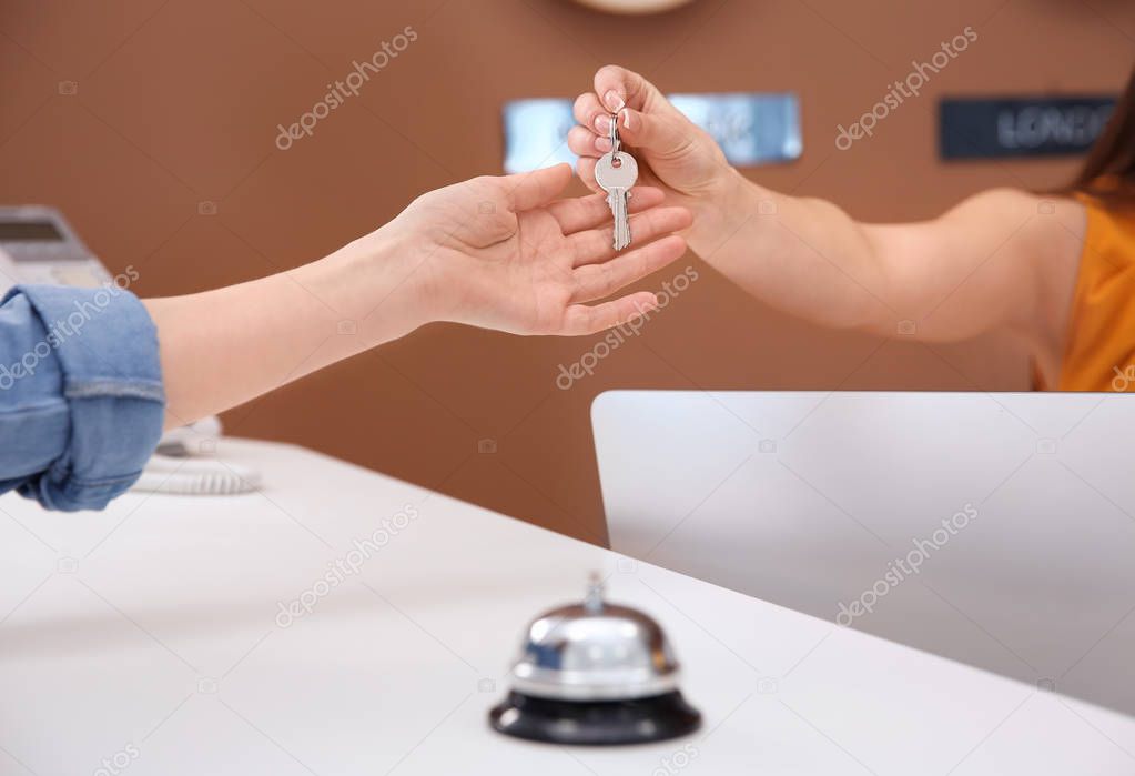 Receptionist handing room key to customer in hotel, closeup