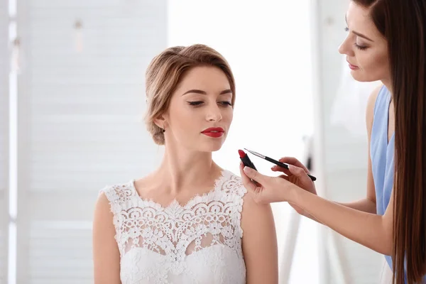 Makeup artist preparing bride before her wedding in room — Stock Photo, Image