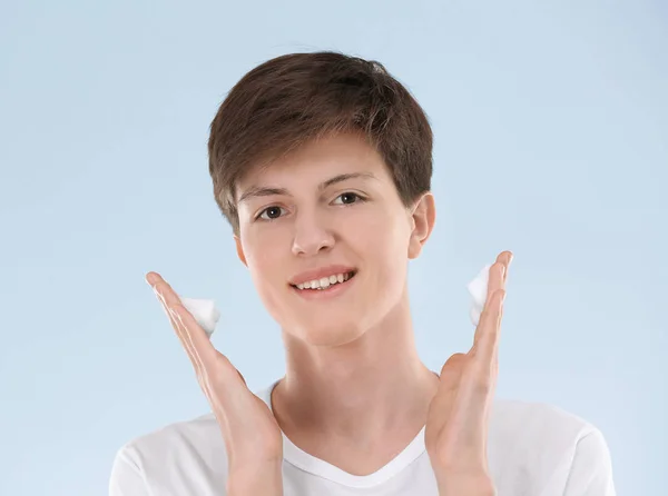 Niño adolescente con problemas de piel aplicando crema anti acné sobre fondo claro — Foto de Stock
