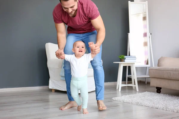 Baby taking first steps with father 's help at home — стоковое фото