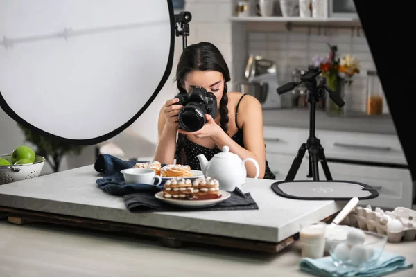 Jovem com câmera profissional tirando foto de comida em estúdio — Fotografia de Stock