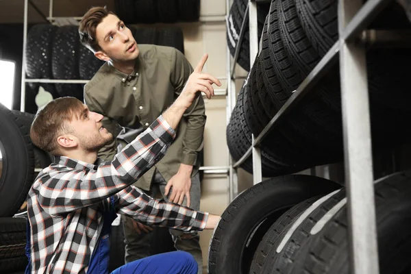 Service center consultant helping customer to choose tire in store