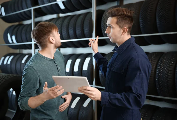 Consultor de centro de serviço ajudando o cliente a escolher pneu na loja — Fotografia de Stock