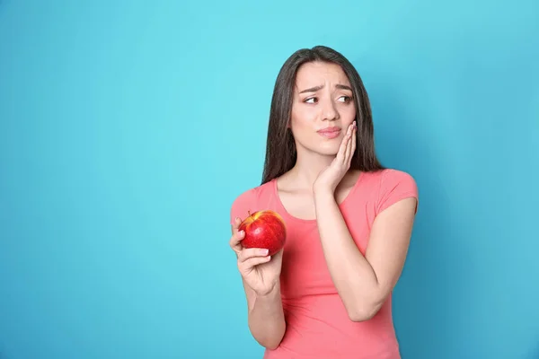 Mujer con dientes sensibles sosteniendo manzana sobre fondo de color — Foto de Stock