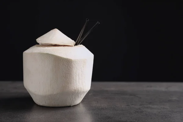 Свіжий кокосовий напій в горіху на столі на чорному тлі — стокове фото