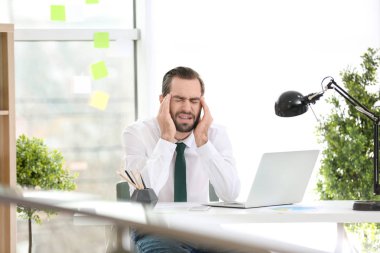 Genç adam ofiste baş ağrısı çekiyor.