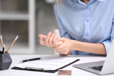 Young woman suffering from wrist pain in office clipart