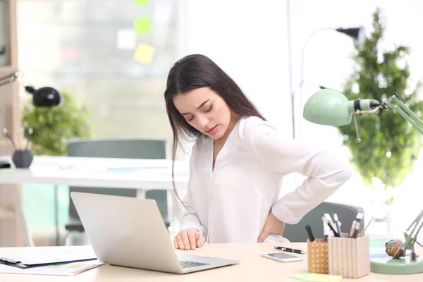 Fiatal nő szenved hátfájás az irodában — Stock Fotó