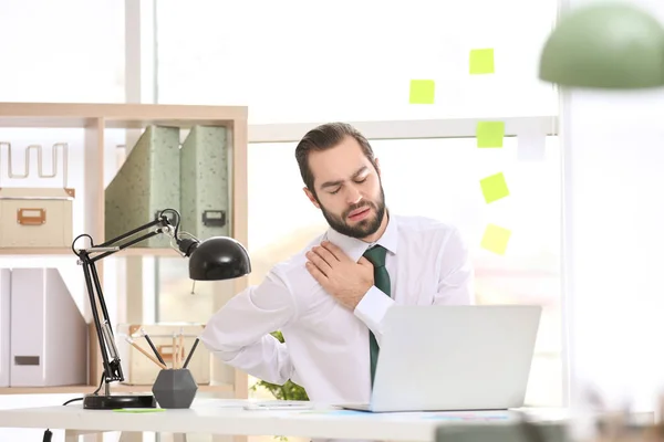 Молодий чоловік, який страждає від болю в плечі в офісі — стокове фото