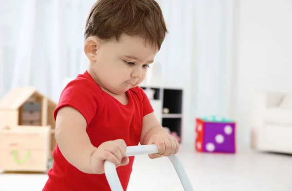 Милый ребенок играет с игрушечным ходунком дома — стоковое фото