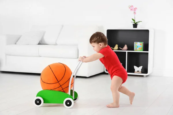 Lindo bebé jugando con el caminante de juguete y la pelota en casa — Foto de Stock