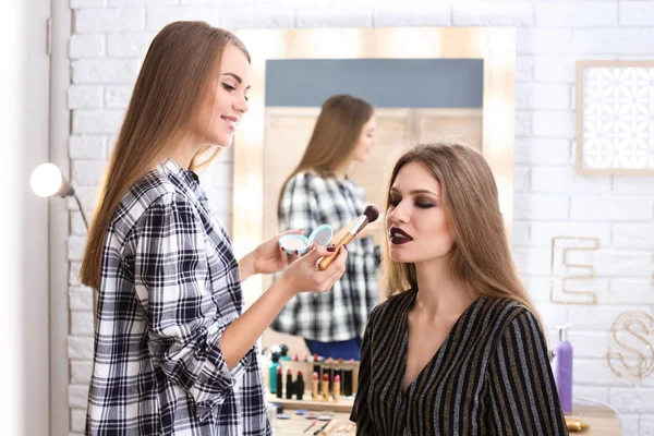 Profesionální make-up umělec, který pracuje s krásnou mladou ženou ve studiu — Stock fotografie