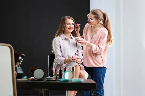 Professional makeup artist working with beautiful young woman in photo studio — Stock Photo, Image