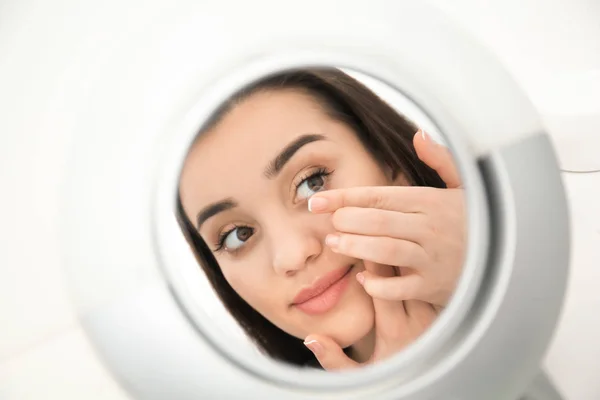 Odbicie lustrzane młodej kobiety umieszczenie soczewki w oku — Zdjęcie stockowe