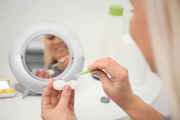 Seniorin nimmt Kontaktlinse aus Container vor Spiegel — Stockfoto