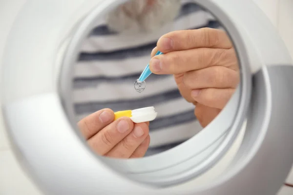 stock image Mirror reflection of senior man taking contact lens from container