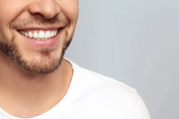 Joven con una hermosa sonrisa sobre fondo gris. Blanqueamiento dental —  Fotos de Stock