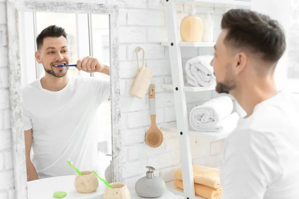 Genç adam banyoda dişlerini fırçalıyor. — Stok fotoğraf
