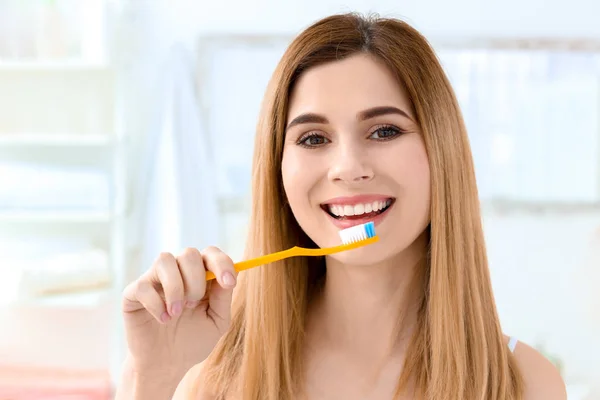 Ung kvinna borsta hennes tänder inomhus — Stockfoto