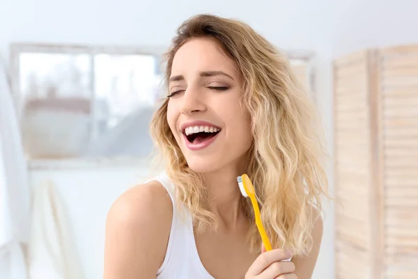 Wanita muda menggosok giginya di kamar mandi — Stok Foto