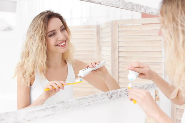 Ung kvinna borsta hennes tänder i badrum — Stockfoto