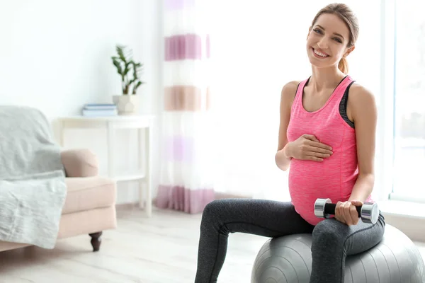 Unga gravid kvinna gör övningar med hantel hemma — Stockfoto