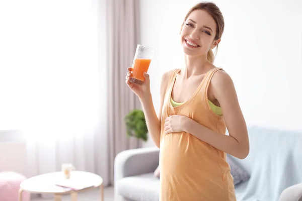Joven embarazada sosteniendo vaso con jugo en casa — Foto de Stock