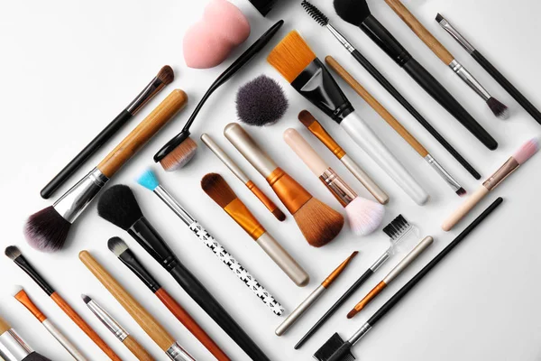 Flat lay composition with makeup brushes of professional artist on white background