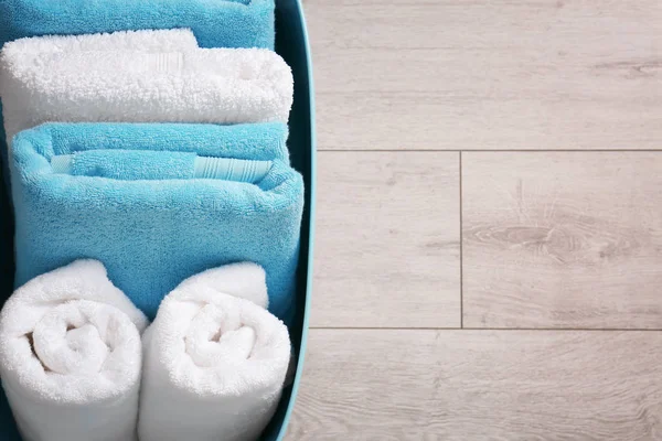 Laundry basket with clean towels on wooden floor — Stock Photo, Image