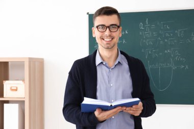 Genç erkek öğretmen sınıfta kitap ayakta ile