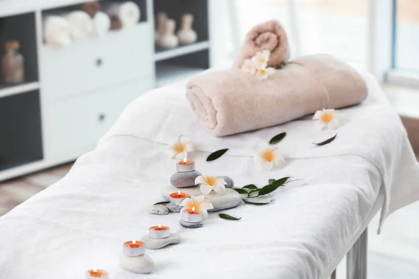 Serviettes, bougies et pierres sur table de massage dans le salon de spa — Photo