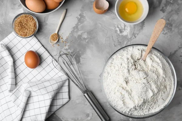 Склад з борошном, яйцями та коричневим цукром на сірому фоні — стокове фото